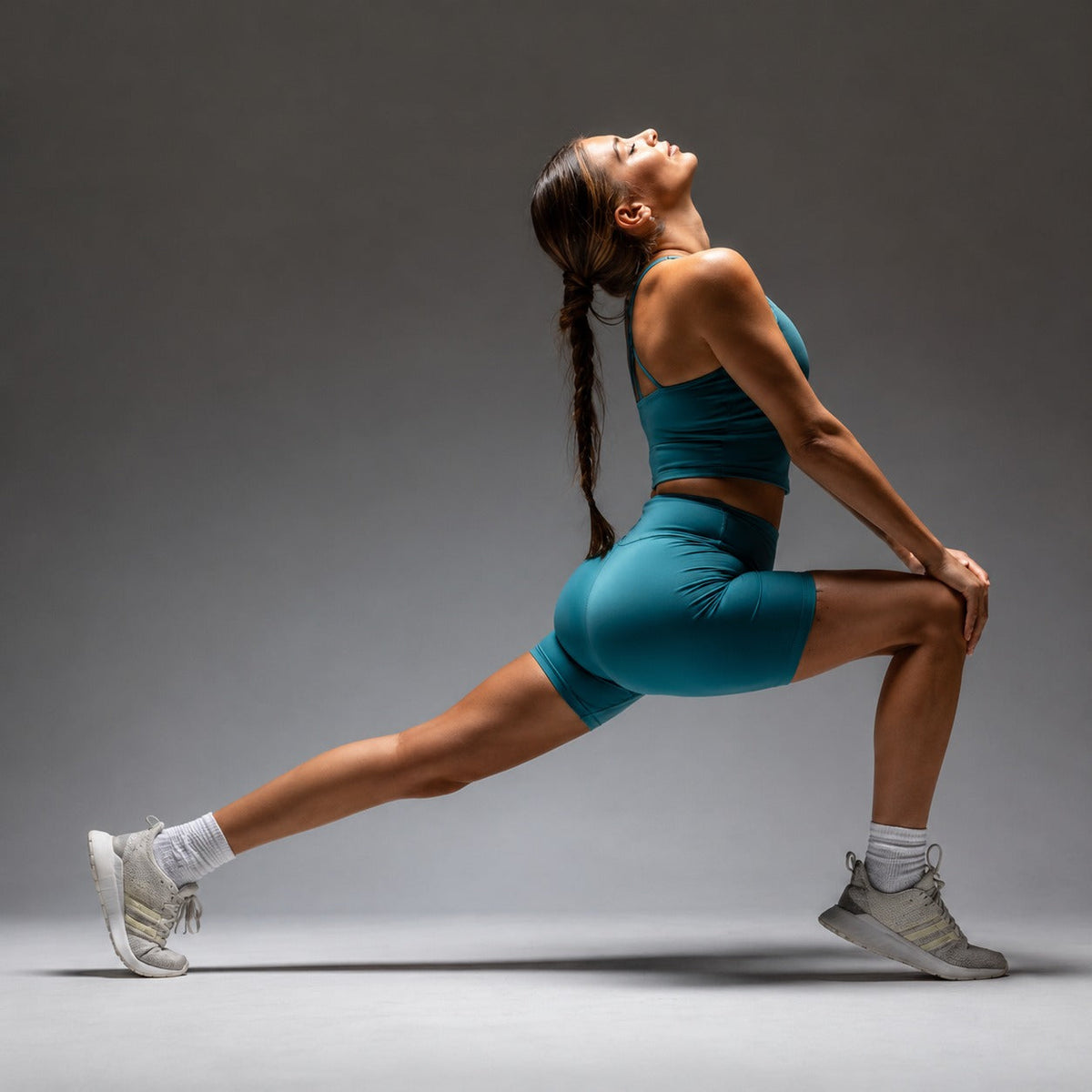 Woman in teal activewear doing a deep lunge stretch