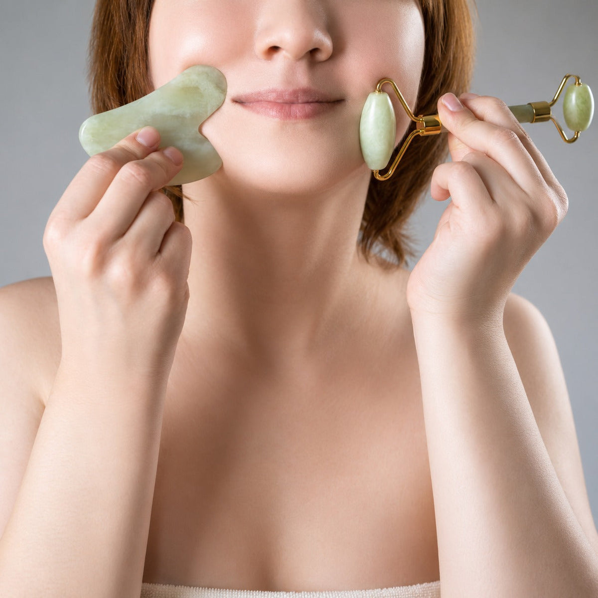 Woman using jade roller and gua sha skincare tools on face